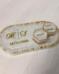Decorative trinket tray with 'M O' initials and date in gold with 2 hexagon ring holders on a light wooden surface