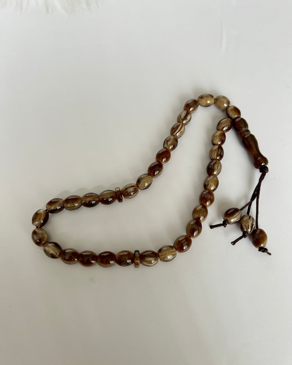 Brown beaded prayer beads on a white background