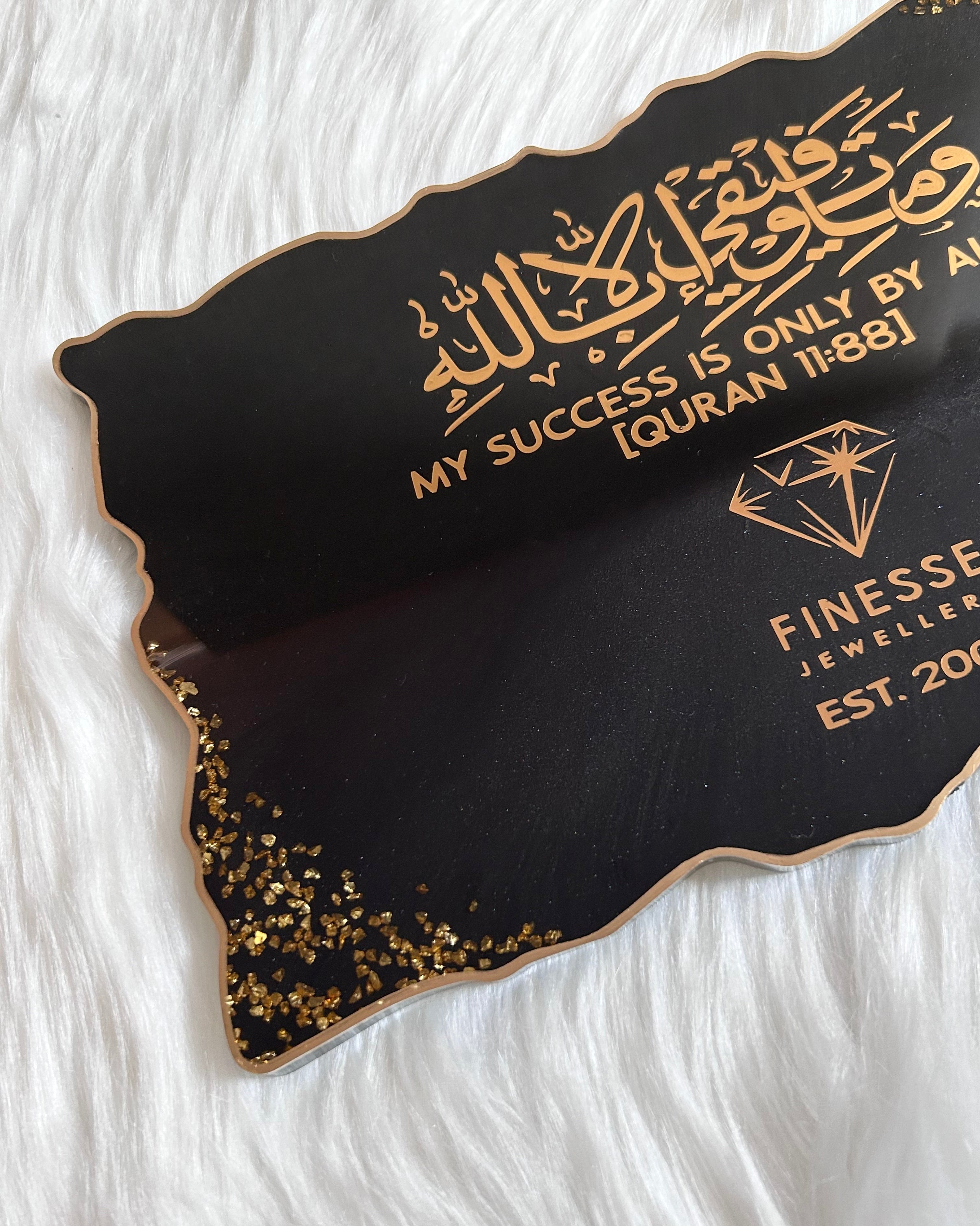 Black and gold personalised business branding plaque/tray with business logo and quran verse 11:88 written in gold on a white fur background background