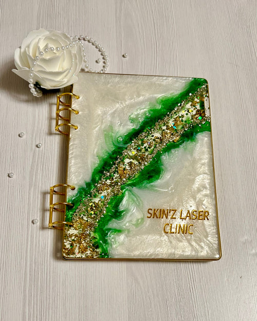 Decorative notebook with gold and green design on a light wooden surface