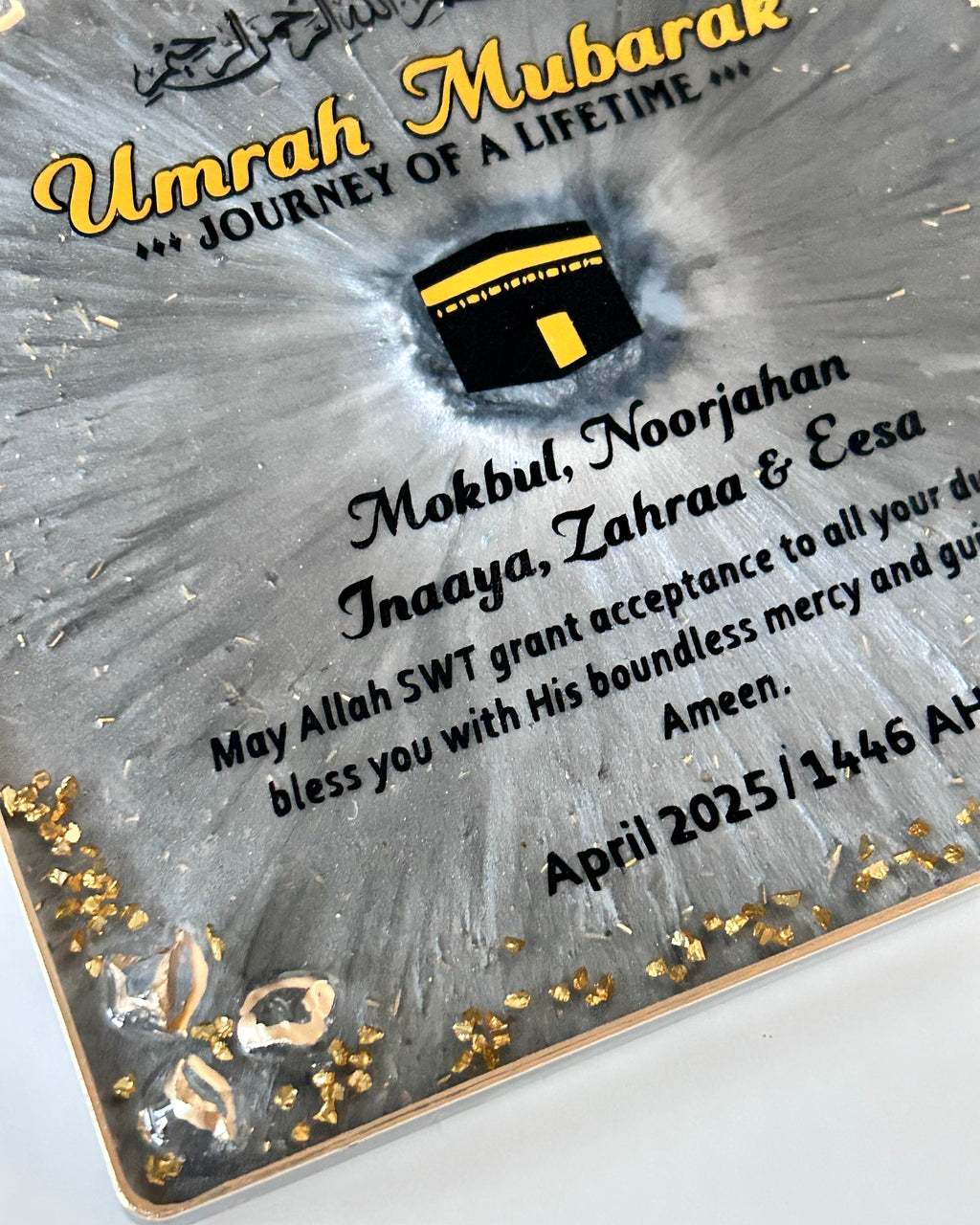 Plaque with 'Umrah Mubarak' text and Kaaba icon on a gray background