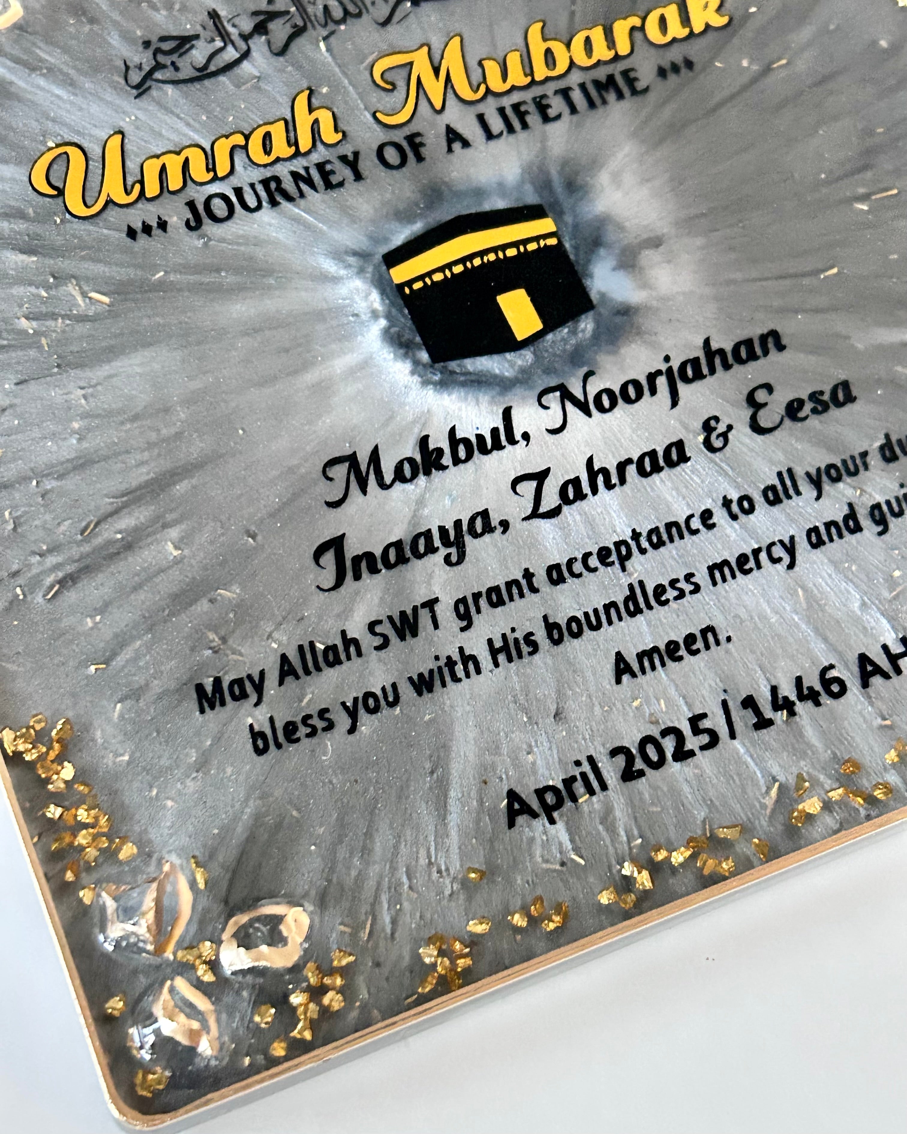 Plaque with 'Umrah Mubarak' text and Kaaba icon on a gray background