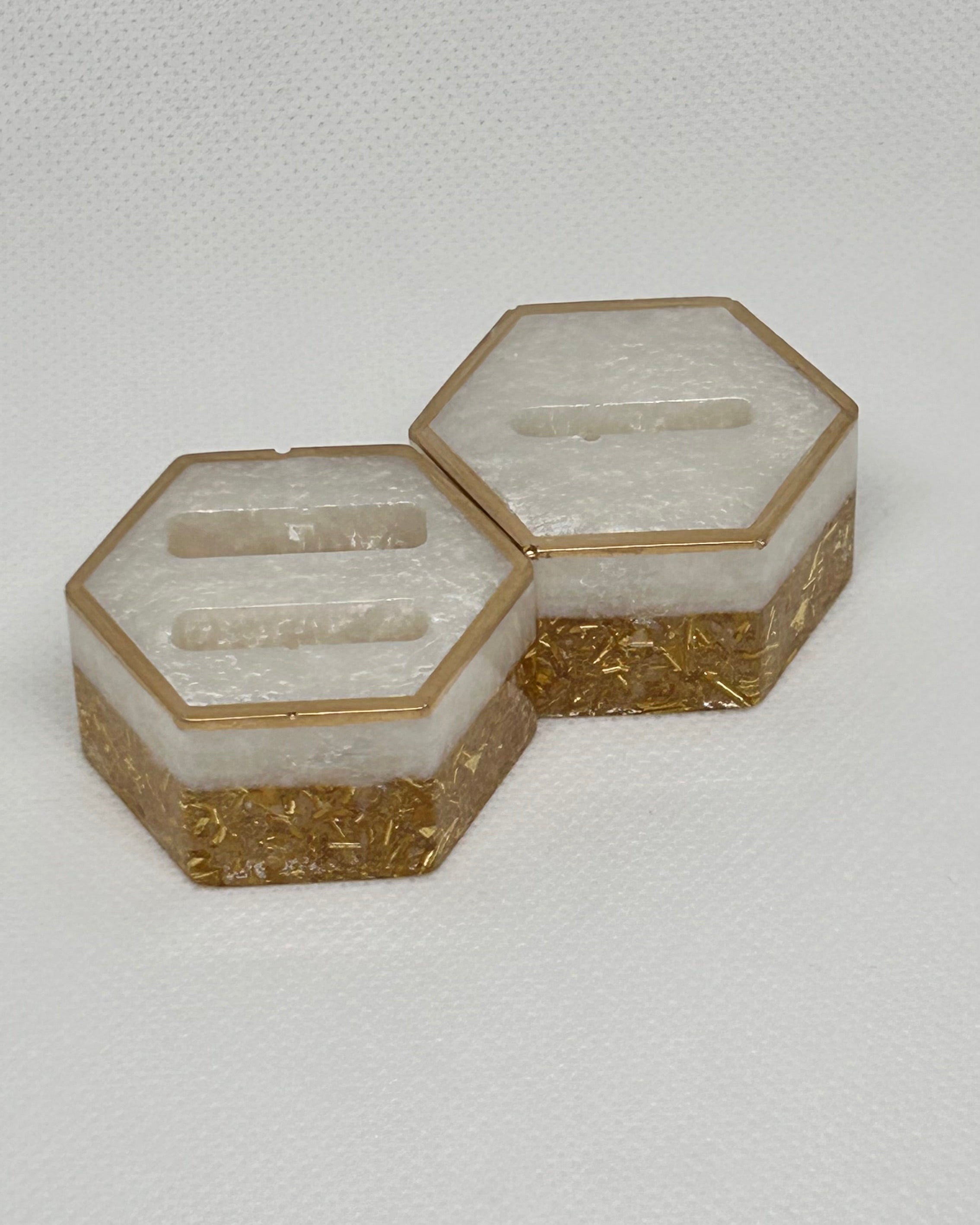 Hexagonal containers with gold accents on a light gray background