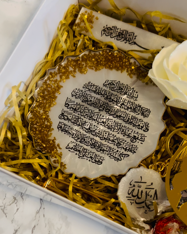 Decorative plate with Arabic text on a bed of gold shreds in a box with bookmark with Arabic text 'Bislmillah' and a keyring with Arabic Text  
