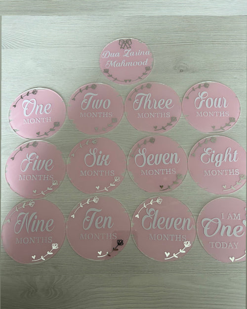 Pink round acrylic discs with numbers and text on a metallic surface