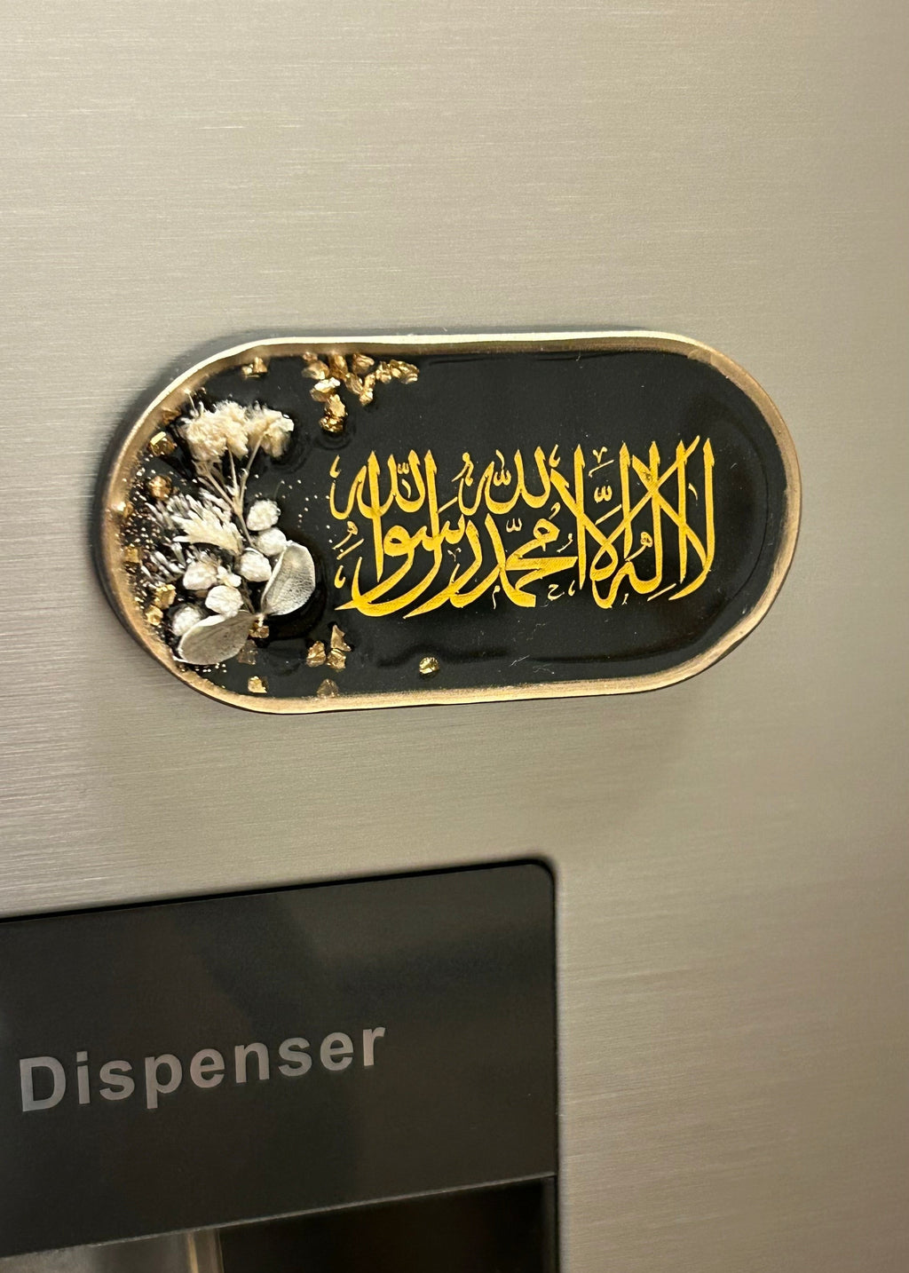 Decorative emblem with Arabic calligraphy on a metallic dispenser