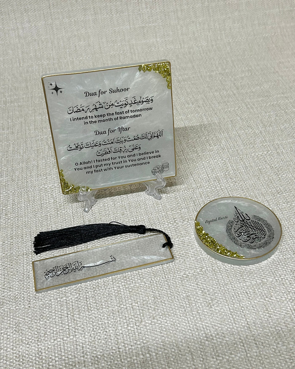 Set of religious items including a plaque with Ramdan suhoor & iftar dua, bookmark with tassel, and small Ayatul Kursi fridge magnet on a textured surface.
