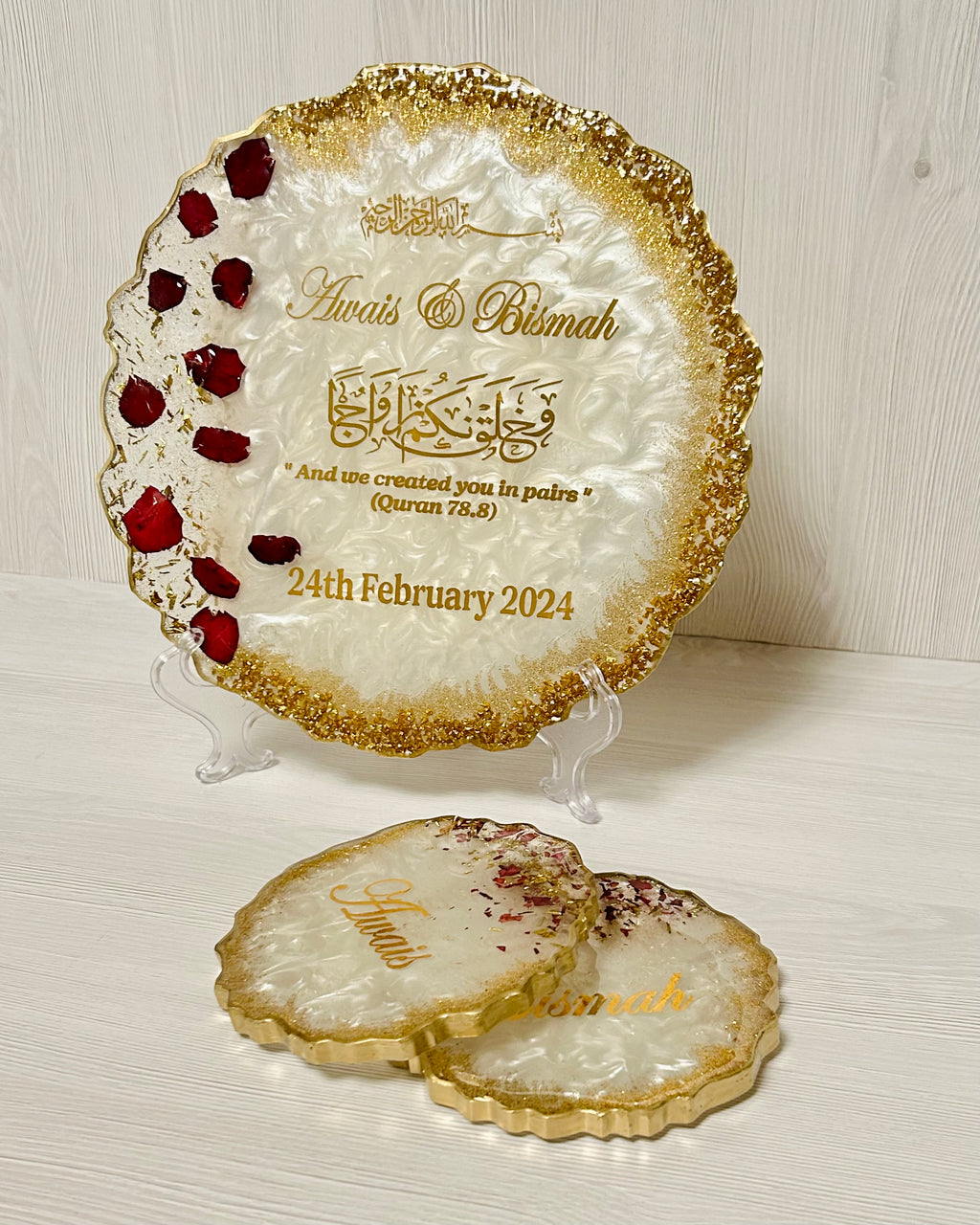 Decorative plate with rose petals and glitter and personalised with couples names with gold edge on a white surface.