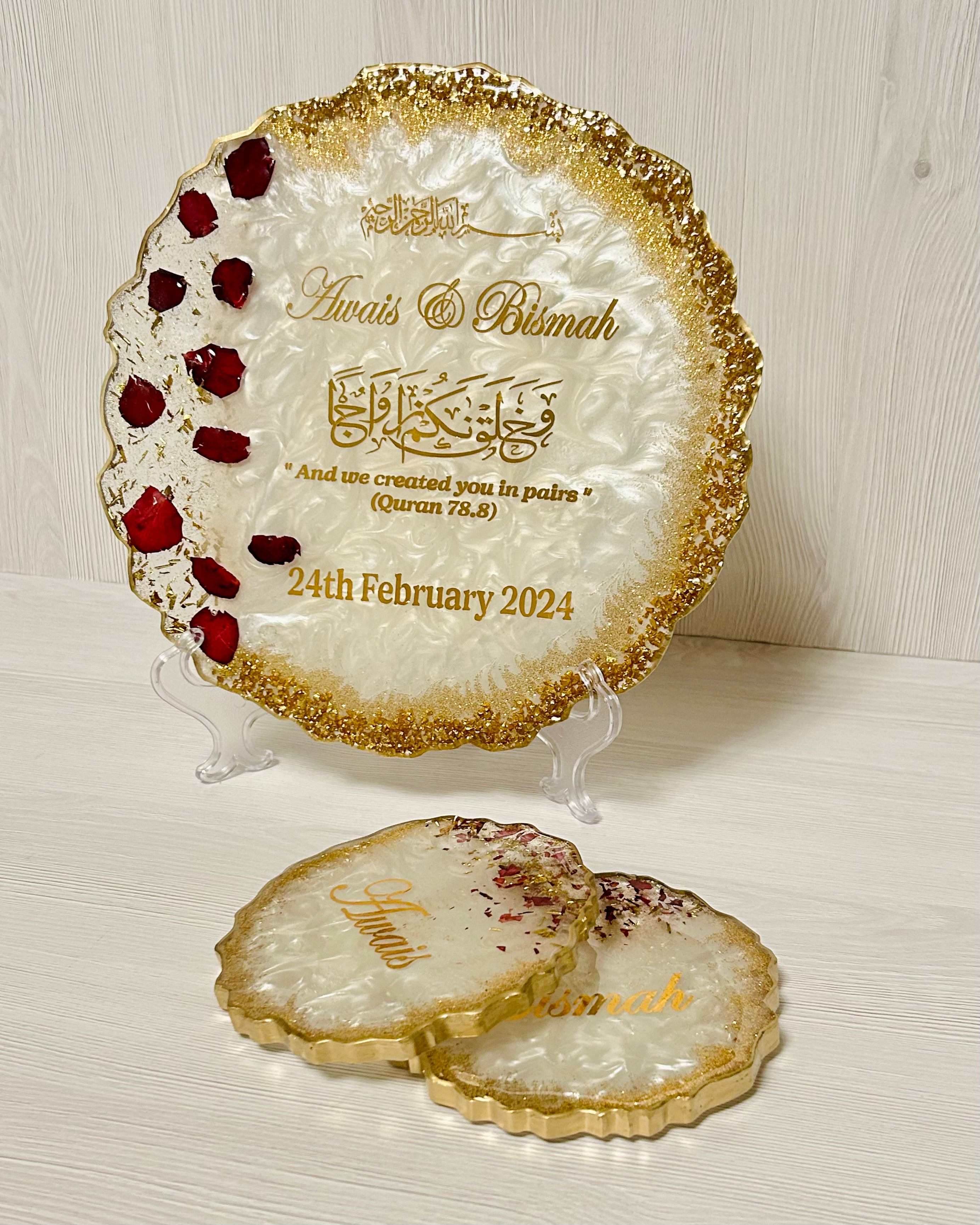 Decorative plate with rose petals and glitter and personalised with couples names with gold edge on a white surface.
