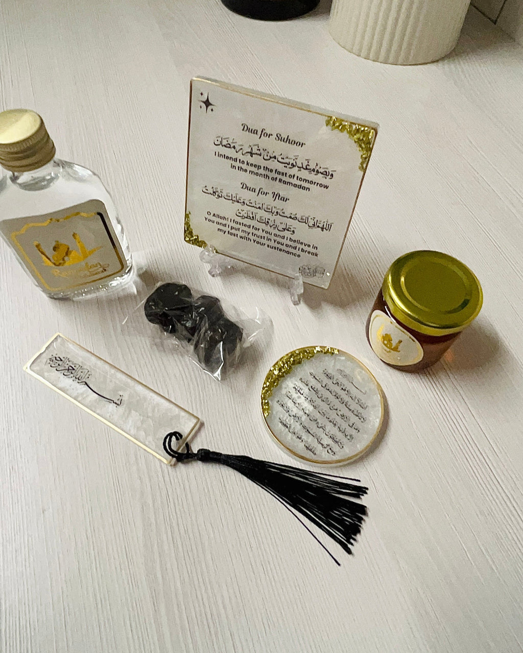 Collection of Ramadan decorative gift items including a Zamzam flask, candle, and small containers on a white surface.