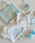 Baby clothing set with 'Prince' text  next to a baby birth stats on a white and blue glitter rectangular shape place with a silver chain for hanging and a ornament with a name on a light background