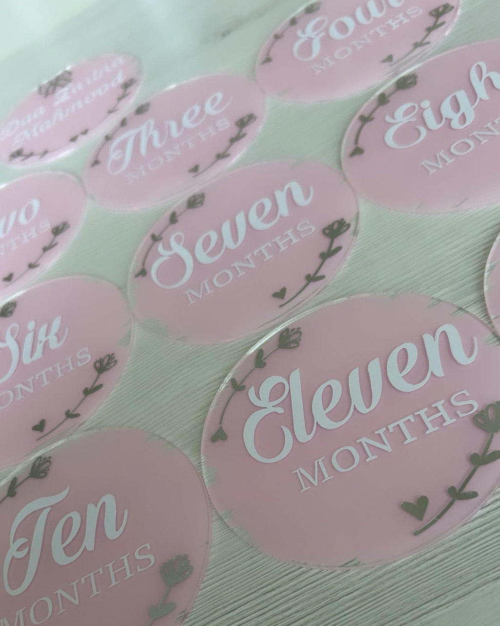 Pink milestone acrylic discs with numbers and 'Months' text on a light background