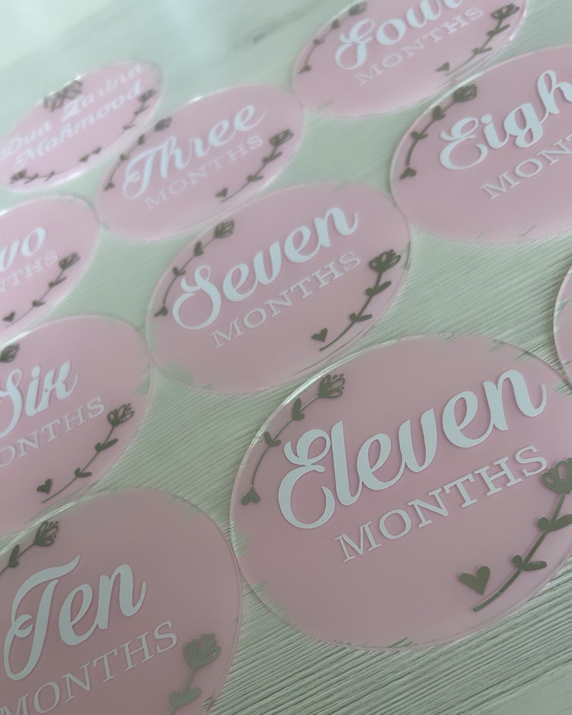 Pink milestone acrylic discs with numbers and 'Months' text on a light background