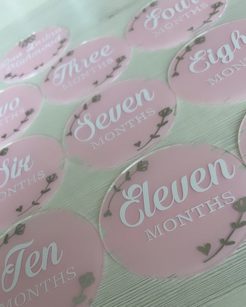 Pink milestone acrylic discs with numbers and 'Months' text on a light background