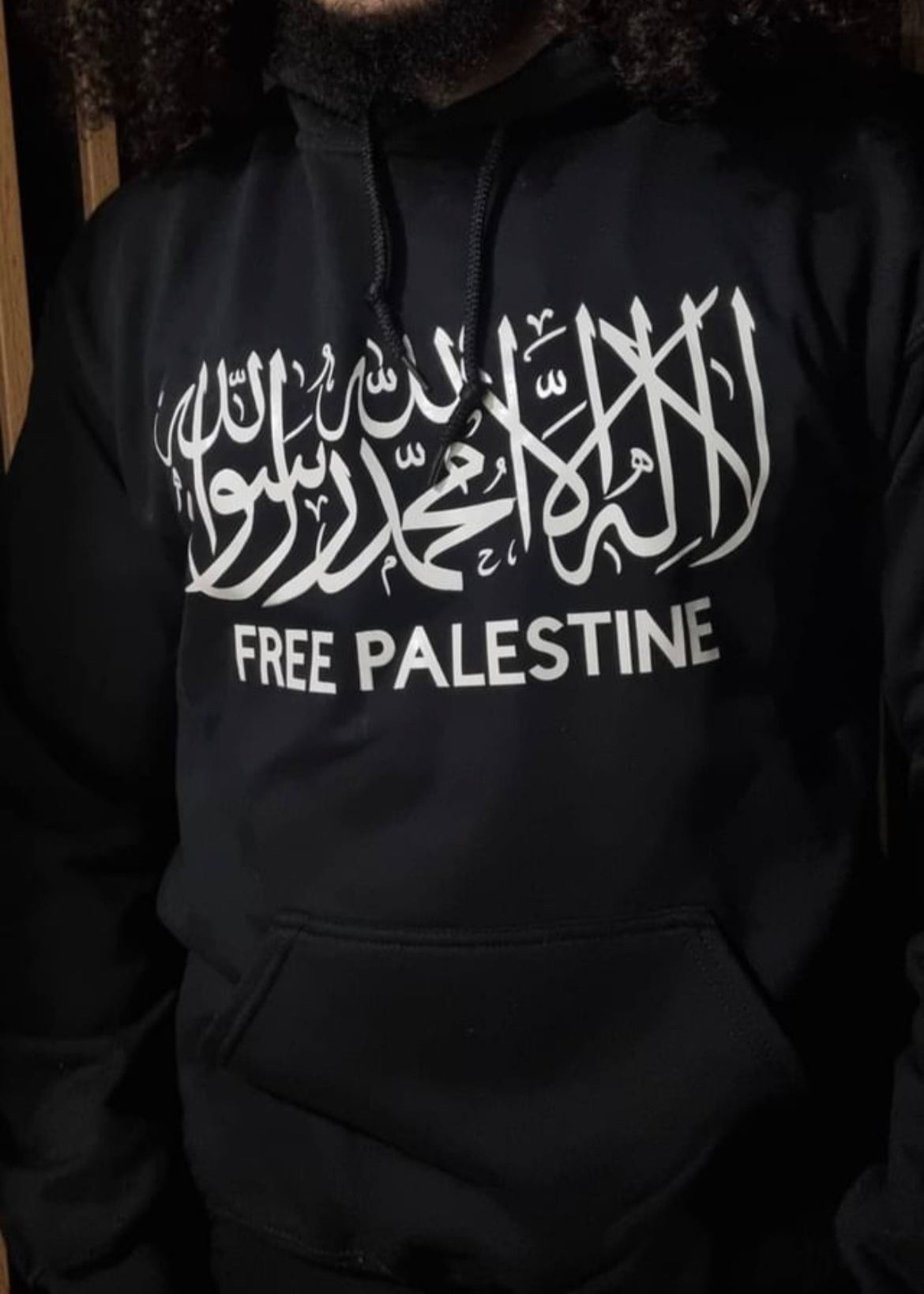 Person wearing a black hoodie with 'Free Palestine' text in white