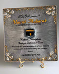 Decorative plaque with 'Umrah Mubarak' text and image of the kaaba design on a marble surface
