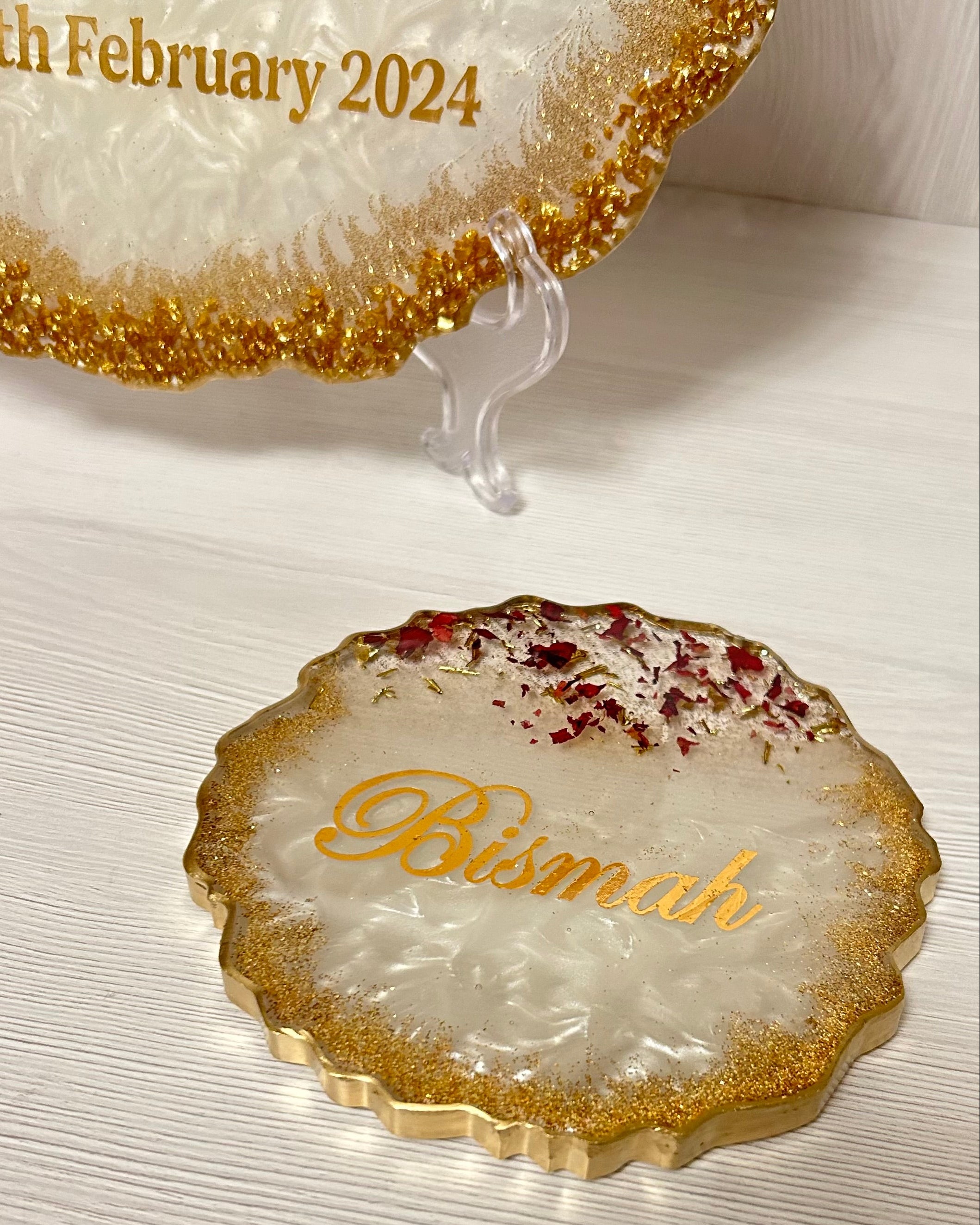 Decorative plate personalised with couples names with gold edge on a white surface.