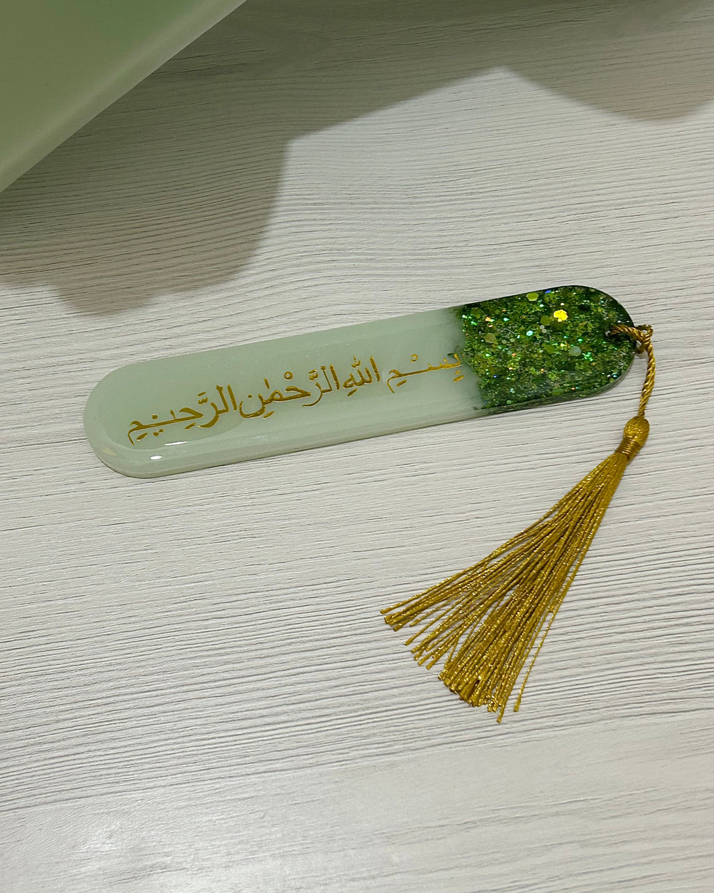 Decorative bookmark with glitter and gold tassel on a light surface