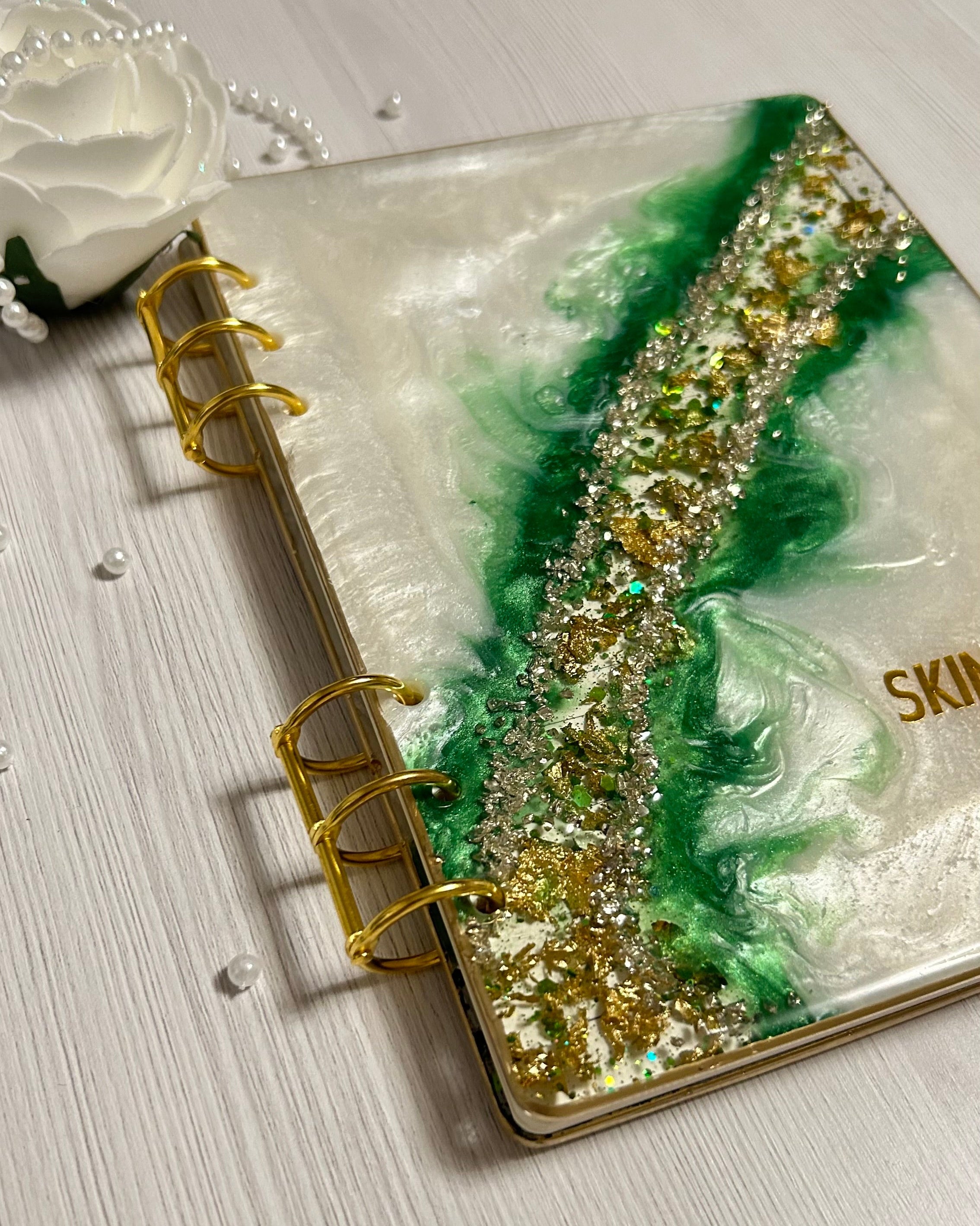 Decorative notebook with green and gold design on a white surface