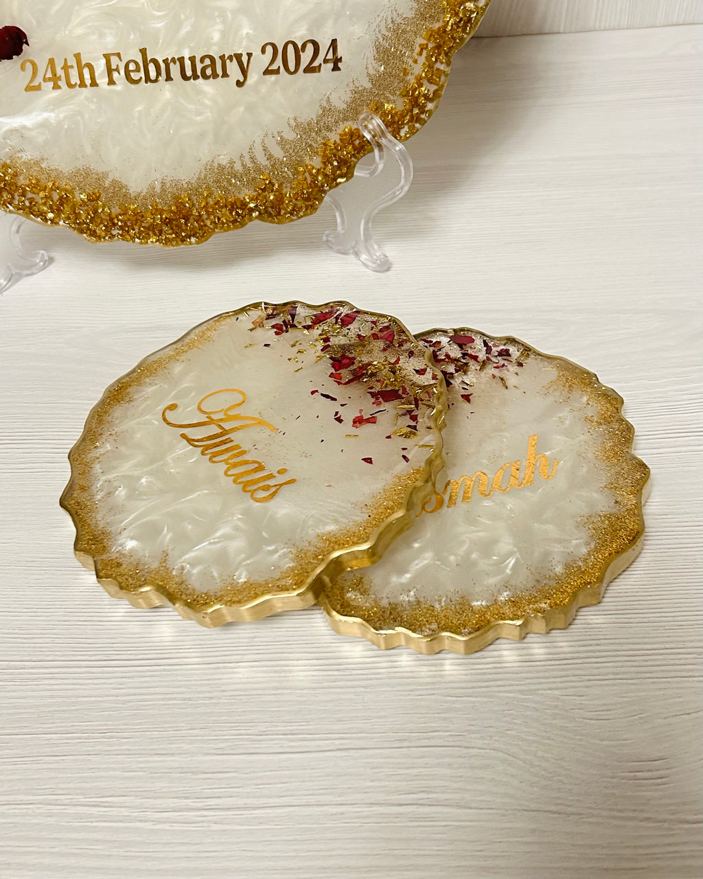 Decorative coasters personalised with couples names with gold edge on a white surface.