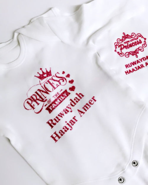 White baby romper with pink glitter vinyl text on a white background